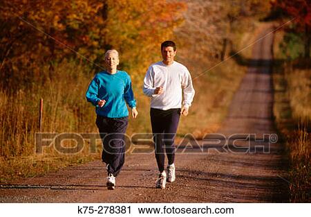 Stock Image - Couple jogging on country road. Fotosearch