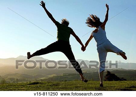 Stock Image - Couple jumbing in sunset. Fotosearch