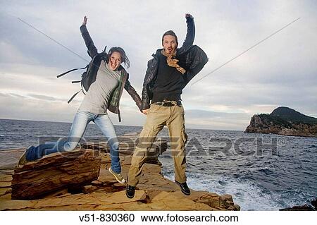 Couple jumping in a cliff by the sea View Large Photo Image Stock Image - Couple jumping in a cliff by the sea. Fotosearch