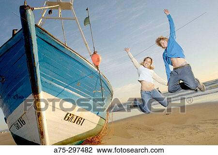 Couple jumping next to stranded fishing boat (Atlantic Ocean) View Large Photo Image Stock Image - Couple jumping next to stranded fishing boat (Atlantic Ocean). Fotosearch