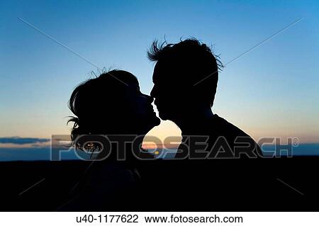 Couple kissing at sunset View Large Photo Image Stock Image - Couple kissing at sunset. Fotosearch