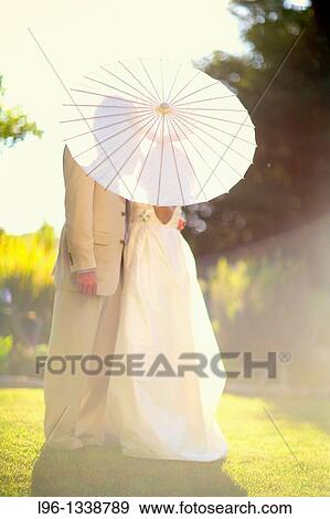 Stock Photo - couple kissing behind umbrella. Fotosearch