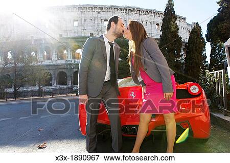 Couple kissing by a red ferrari in front of the Roman Colosseum in Rome Italy View Large Photo Image Stock Photo - Couple kissing by a red ferrari in front of the Roman Colosseum in Rome Italy. Fotosearch