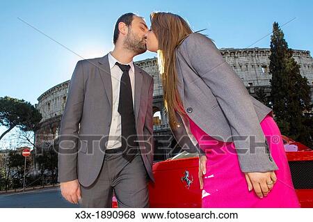 Couple kissing by a red ferrari in front of the Roman Colosseum in Rome Italy View Large Photo Image Stock Photo - Couple kissing by a red ferrari in front of the Roman Colosseum in Rome Italy. Fotosearch