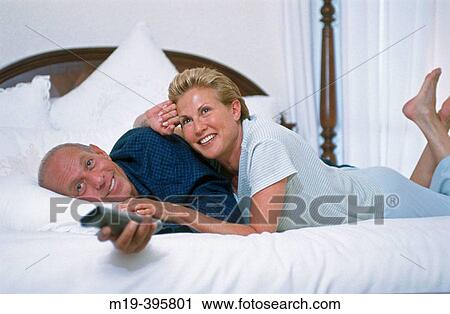 couple laughing on a bed watching TV View Large Photo Image Stock Image - couple laughing on a bed watching TV. Fotosearch