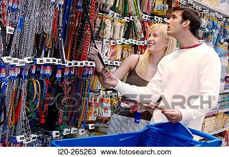 Stock Image - Couple looking at electronic price displays at the pets section of Eroski shopping center. These displays are updated by remote control. Urbil. Usurbil. Guipuzcoa. Basque Country. Spain. Fotosearch