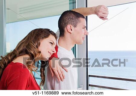 Stock Photo - Couple looking at the sea from home. Fotosearch
