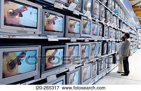 Couple looking at TVs in shopping center View Large Photo Image Stock Photo - Couple looking at TVs in shopping center. Fotosearch