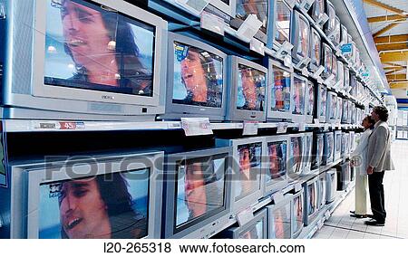 Couple looking at TVs in shopping center View Large Photo Image Stock Photo - Couple looking at TVs in shopping center. Fotosearch