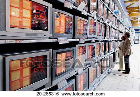 Couple looking at TVs in shopping center View Large Photo Image Stock Photograph - Couple looking at TVs in shopping center. Fotosearch