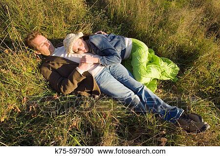 Couple lying in field in the sunshine View Large Photo Image Stock Image - Couple lying in field in the sunshine. Fotosearch
