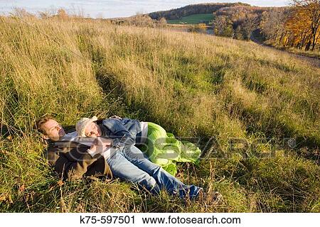 Stock Image - Couple lying in field in the sunshine. Fotosearch