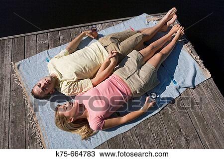 Couple lying on dock in the sun View Large Photo Image Stock Image - Couple lying on dock in the sun. Fotosearch