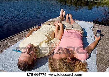 Stock Photography - Couple lying on dock in the sun. Fotosearch