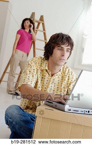Couple moving home, the boy with laptop while the girl with mobile phone View Large Photo Image Stock Image - Couple moving home, the boy with laptop while the girl with mobile phone. Fotosearch