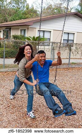 Couple multi ethnics dating in park on swing with fun and Asian Hispanic ethnic laughter near home in playground View Large Photo Image Stock Photo - Couple multi ethnics dating in park on swing with fun and Asian Hispanic ethnic laughter near home in playground. Fotosearch