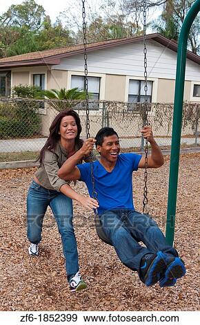 Couple multi ethnics dating in park on swing with fun and Asian Hispanic ethnic laughter near home in playground View Large Photo Image Stock Photo - Couple multi ethnics dating in park on swing with fun and Asian Hispanic ethnic laughter near home in playground. Fotosearch