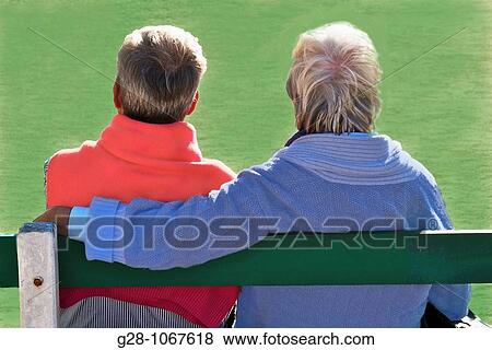 couple of 2 seniors sitting on a bench, in a garden, on a green background, seen from behind, looking in front of them, concept image View Large Photo Image Stock Photo - couple of 2 seniors sitting on a bench, in a garden, on a green background, seen from behind, looking in front of them, concept image. Fotosearch