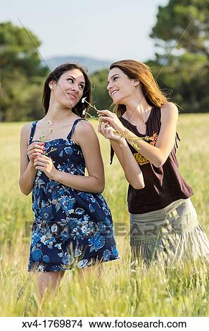 Couple of girls playing and enjoyment whit flowers in the countryside View Large Photo Image Picture - Couple of girls playing and enjoyment whit flowers in the countryside. Fotosearch