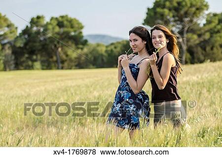 Couple of girls playing and enjoyment whit flowers in the countryside View Large Photo Image Stock Photo - Couple of girls playing and enjoyment whit flowers in the countryside. Fotosearch
