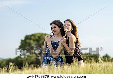 Couple of girls playing and enjoyment whit flowers in the countryside View Large Photo Image Stock Photo - Couple of girls playing and enjoyment whit flowers in the countryside. Fotosearch