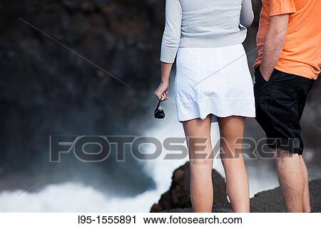 Couple of tourists at Los Hervideros the Boiling ones, natural tourist attraction on the coast where solidified volcano lava flows have been eroded by the Atlantic ocean resulting in wave induced geysers, spills and mist, Lanzarote, Canary Islands, Spain View Large Photo Image Stock Image - Couple of tourists at Los Hervideros the Boiling ones, natural tourist attraction on the coast where solidified volcano lava flows have been eroded by the Atlantic ocean resulting in wave induced geysers, spills and mist, Lanzarote, Canary Islands, Spain. Fotosearch