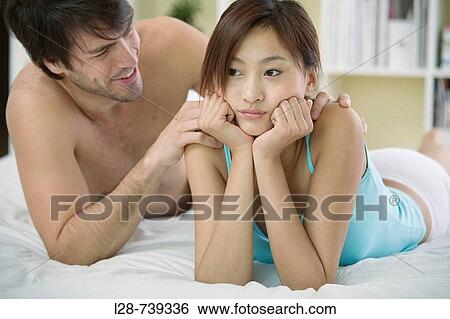 Stock Photograph - Couple on bed, multi-ethnic. Fotosearch