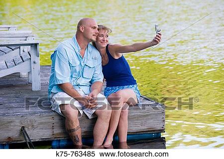 Stock Photography - couple on dock taking photo with camera phone. Fotosearch