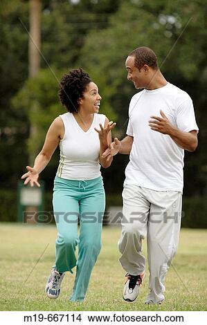 Picture - Couple playfully jogging in a park. Fotosearch