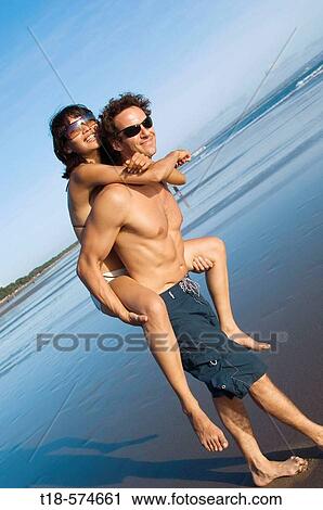Stock Image - couple playing on beach. Fotosearch