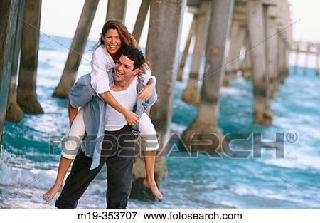 Stock Photo - Couple playing under pier. Fotosearch