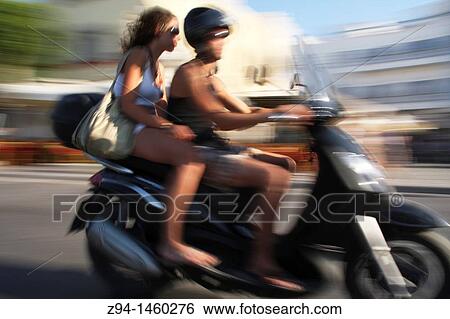 Stock Photograph - Couple riding scooter. Fotosearch