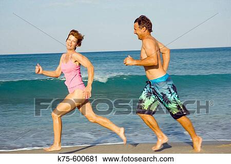 Couple running along the shoreline View Large Photo Image Stock Image - Couple running along the shoreline. Fotosearch