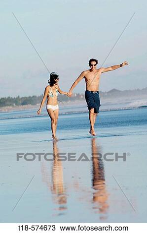 Stock Image - couple running and jumping on beach. Fotosearch