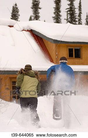 Couple running away from camera on snowshoes towards a winter lodge. View Large Photo Image Stock Photography - Couple running away from camera on snowshoes towards a winter lodge.. Fotosearch