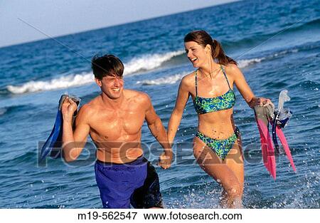 Stock Photo - couple running holding hands on the beach. Fotosearch