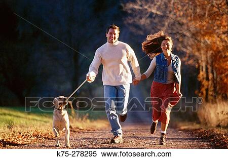 Couple running with their dog on a country road View Large Photo Image Stock Photography - Couple running with their dog on a country road. Fotosearch