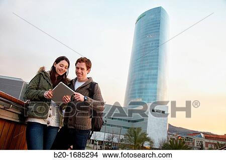 Picture - Couple searching on digital tablet in city, digital tablet, Iberdrola Tower, Abandoibarra, Bilbao, Bizkaia, Basque Country, Spain. Fotosearch