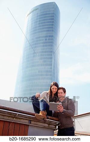 Couple searching on digital tablet in city, digital tablet, Iberdrola Tower, Abandoibarra, Bilbao, Bizkaia, Basque Country, Spain View Large Photo Image Stock Image - Couple searching on digital tablet in city, digital tablet, Iberdrola Tower, Abandoibarra, Bilbao, Bizkaia, Basque Country, Spain. Fotosearch