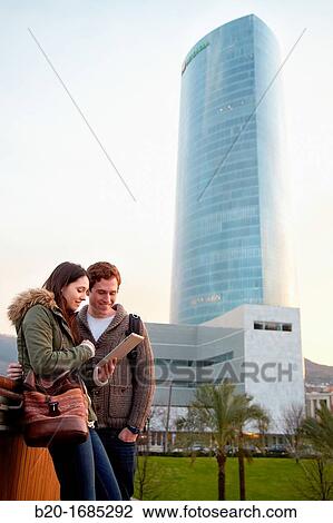 Couple searching on digital tablet in city, digital tablet, Iberdrola Tower, Abandoibarra, Bilbao, Bizkaia, Basque Country, Spain View Large Photo Image Stock Image - Couple searching on digital tablet in city, digital tablet, Iberdrola Tower, Abandoibarra, Bilbao, Bizkaia, Basque Country, Spain. Fotosearch