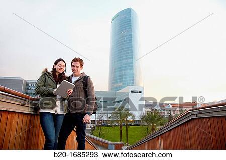 Couple searching on digital tablet in city, digital tablet, Iberdrola Tower, Abandoibarra, Bilbao, Bizkaia, Basque Country, Spain View Large Photo Image Stock Image - Couple searching on digital tablet in city, digital tablet, Iberdrola Tower, Abandoibarra, Bilbao, Bizkaia, Basque Country, Spain. Fotosearch