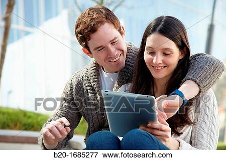 Stock Photo - Couple searching on digital tablet in city, digital tablet, Iberdrola Tower, Abandoibarra, Bilbao, Bizkaia, Basque Country, Spain. Fotosearch