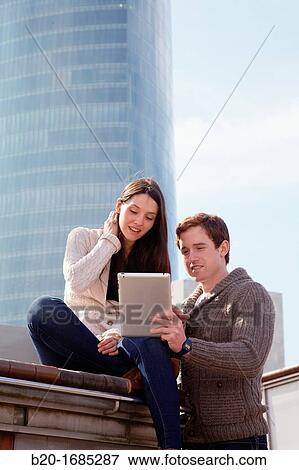 Stock Photo - Couple searching on digital tablet in city, digital tablet, Iberdrola Tower, Abandoibarra, Bilbao, Bizkaia, Basque Country, Spain. Fotosearch