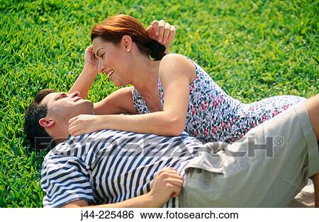 Couple sharing a moment on the grass View Large Photo Image Stock Photograph - Couple sharing a moment on the grass. Fotosearch