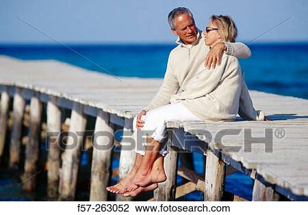Couple sitting down in a wooden footbridge over the sea View Large Photo Image Stock Image - Couple sitting down in a wooden footbridge over the sea. Fotosearch