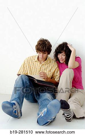 Couple sitting down on the floor watching a book View Large Photo Image Stock Image - Couple sitting down on the floor watching a book. Fotosearch