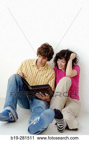 Couple sitting down on the floor watching a book View Large Photo Image Stock Image - Couple sitting down on the floor watching a book. Fotosearch