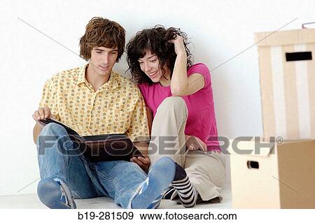 Couple sitting down on the floor watching a book View Large Photo Image Stock Photo - Couple sitting down on the floor watching a book. Fotosearch