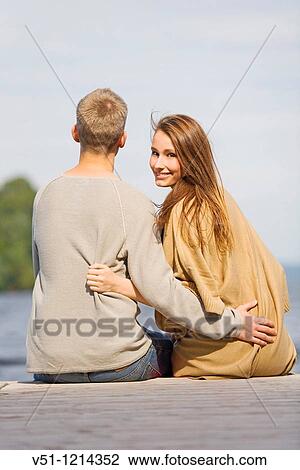 Couple sitting in a pier View Large Photo Image Stock Image - Couple sitting in a pier. Fotosearch