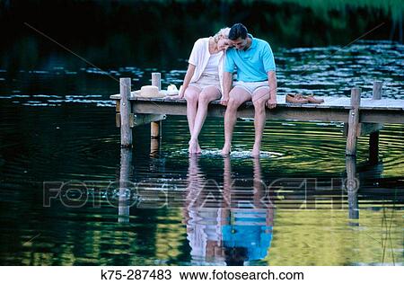 couple sitting on a dock with their feet in the water View Large Photo Image Stock Image - couple sitting on a dock with their feet in the water. Fotosearch